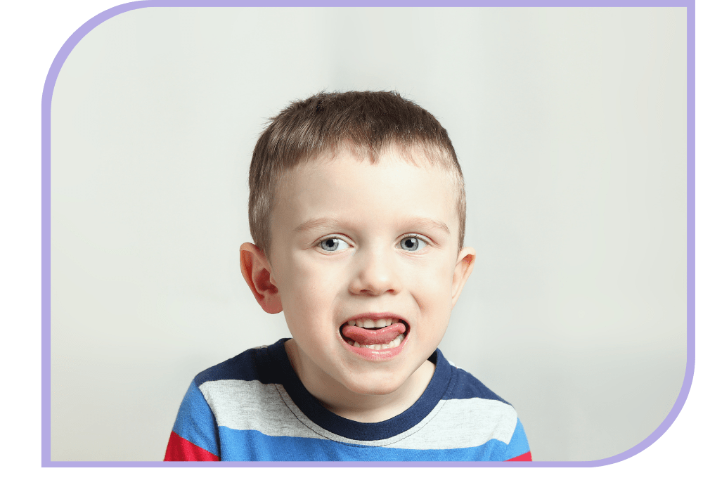 A young boy looks at the camera with his tongue poking out between his teeth. Speech Therapy | Able Kids Therapy